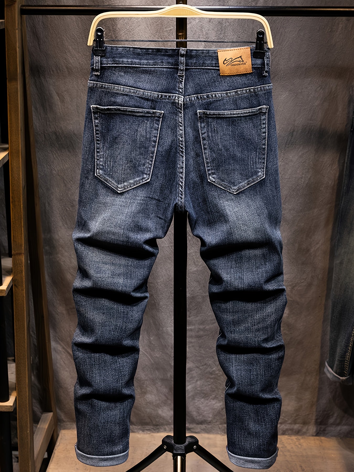 Blue jeans on a hanger against a neutral background